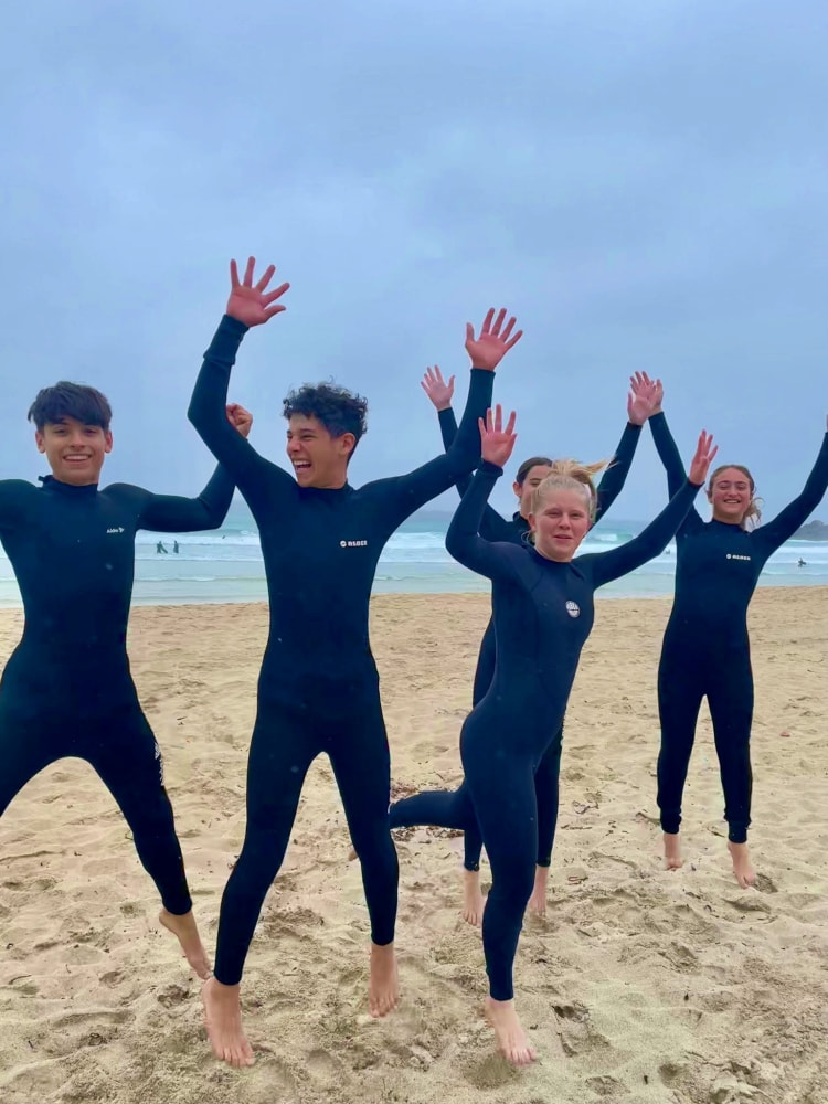 Teenagers jumping for joy after surf lesson